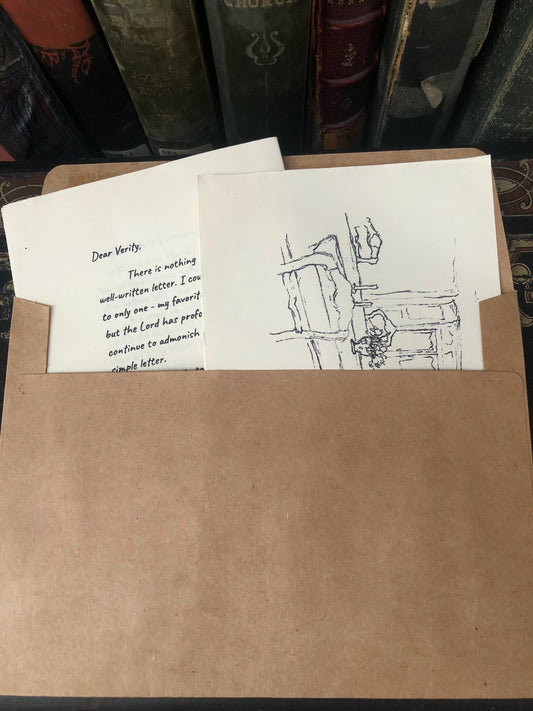 Verity Letters is a Christian letter subscription. The image is of a brown envelope with the letter and sketch  shown from the top. Old books are seen in the background. 